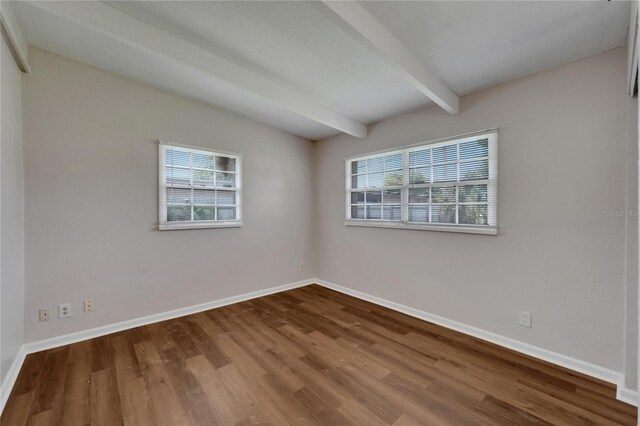 unfurnished room featuring beam ceiling, hardwood / wood-style flooring, and plenty of natural light