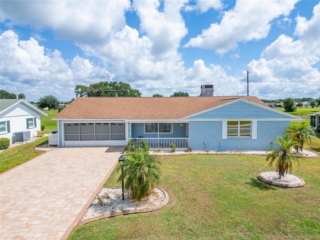 ranch-style house featuring cooling unit, a garage, covered porch, and a front lawn