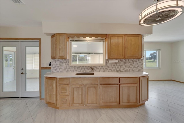 kitchen featuring light brown cabinetry, sink, french doors, and tasteful backsplash