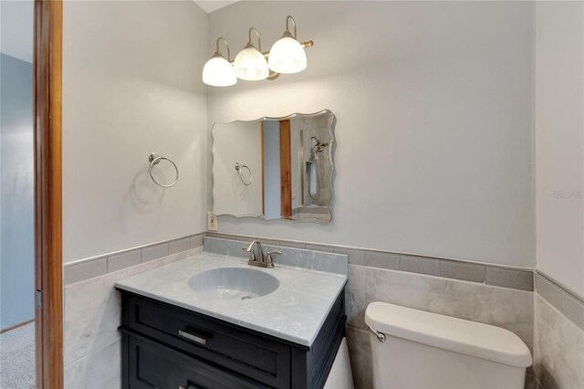 609 Fox Hills Dr, Sun City Center, FL 33573 - bathroom featuring toilet, vanity, a wainscoted wall, and tile walls