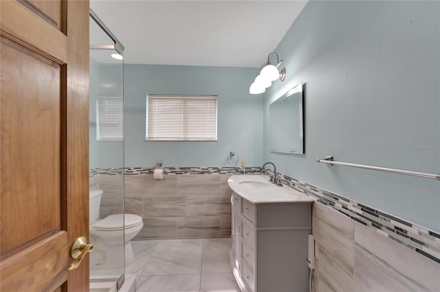 bathroom with tile patterned flooring, vanity, toilet, and tile walls