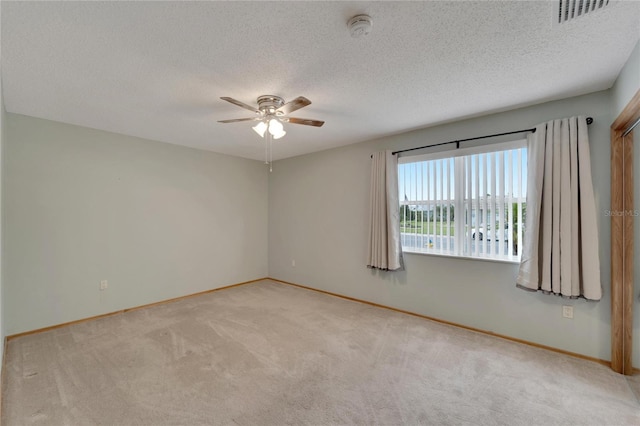 empty room with a textured ceiling, light colored carpet, and ceiling fan