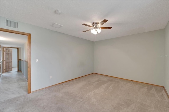 empty room with ceiling fan, a textured ceiling, and light carpet