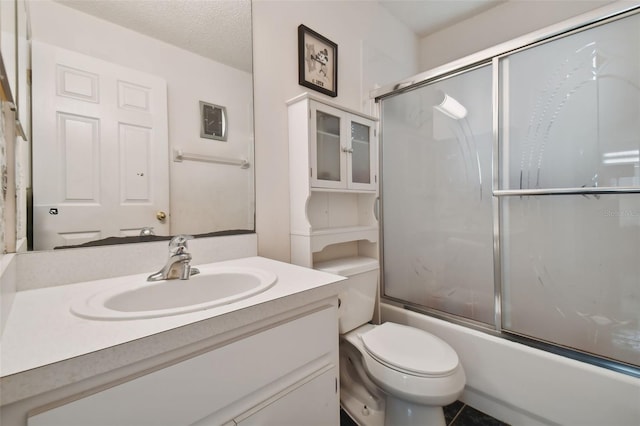 full bathroom featuring tile patterned flooring, bath / shower combo with glass door, a textured ceiling, toilet, and vanity