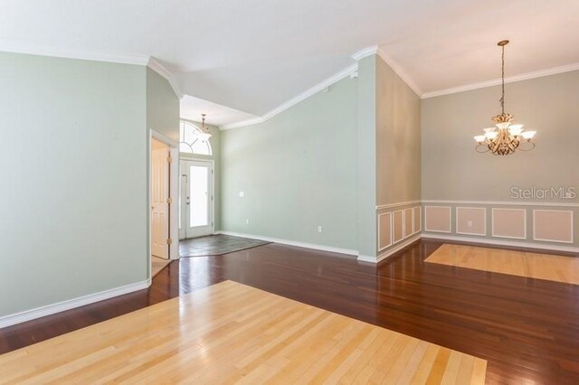 spare room featuring ornamental molding, hardwood / wood-style floors, and a chandelier