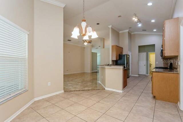 kitchen featuring light tile patterned flooring, crown molding, refrigerator, ceiling fan with notable chandelier, and pendant lighting