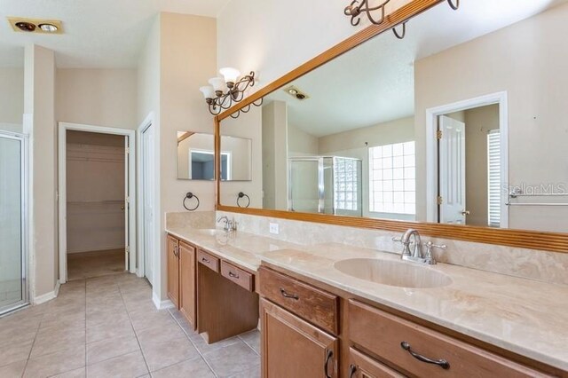 bathroom featuring vaulted ceiling, tile patterned floors, walk in shower, and dual bowl vanity