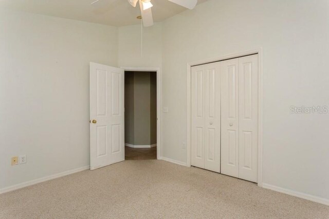 unfurnished bedroom featuring light carpet, a closet, a towering ceiling, and ceiling fan