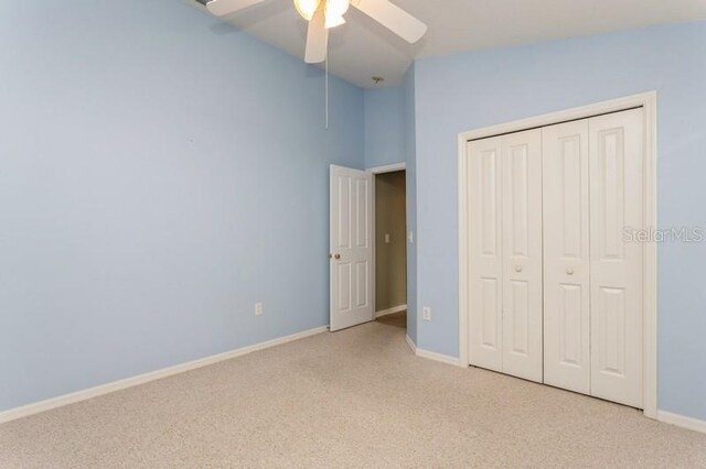 unfurnished bedroom with high vaulted ceiling, light carpet, ceiling fan, and a closet