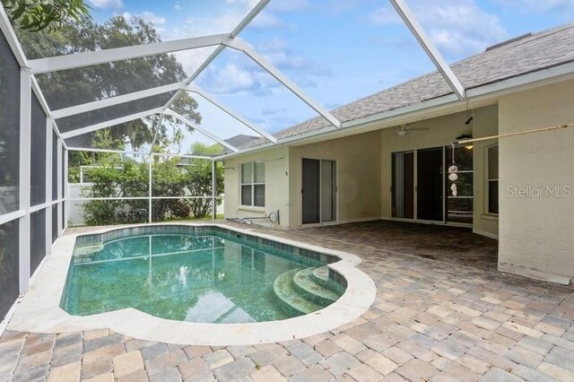 view of swimming pool featuring a patio, ceiling fan, and glass enclosure