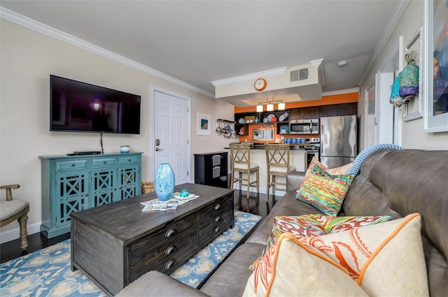 living area with baseboards, visible vents, crown molding, and wood finished floors