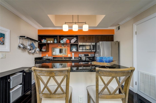 kitchen featuring appliances with stainless steel finishes, dark countertops, a breakfast bar, and visible vents