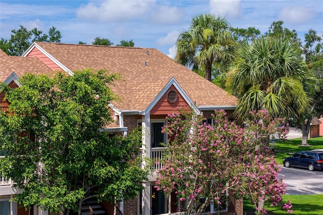 obstructed view of property with a shingled roof and brick siding