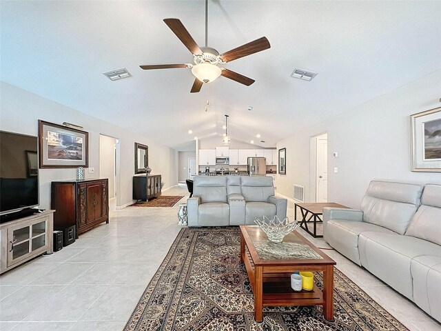 living room with ceiling fan, light tile patterned floors, and vaulted ceiling