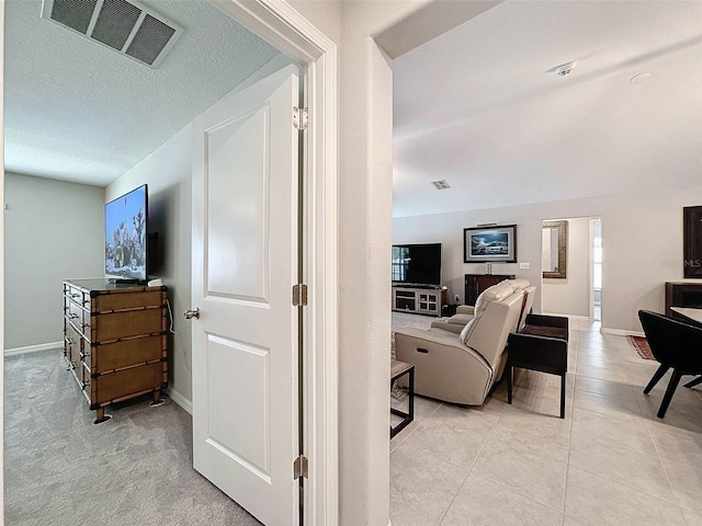 hall featuring light colored carpet and a textured ceiling