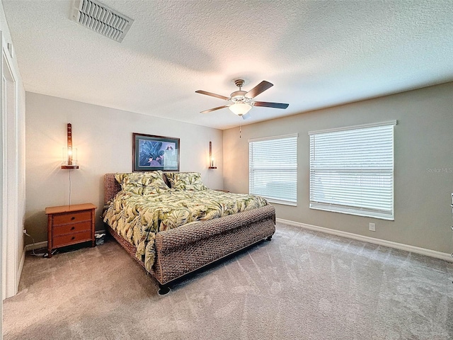 bedroom featuring ceiling fan, carpet floors, and a textured ceiling