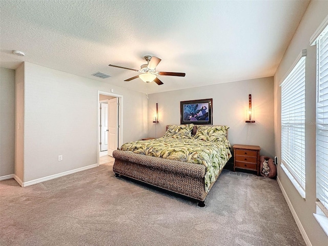 carpeted bedroom featuring a textured ceiling, multiple windows, and ceiling fan