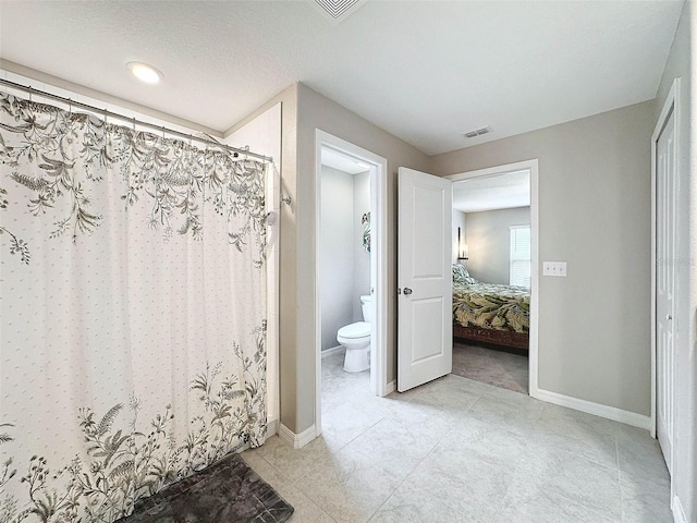 bathroom with a shower with curtain, tile patterned floors, and toilet