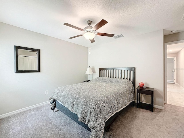 carpeted bedroom featuring ceiling fan and a textured ceiling