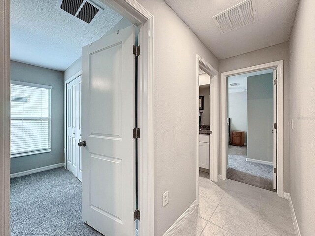 hallway featuring light tile patterned flooring and a textured ceiling