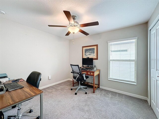 office featuring a textured ceiling, light carpet, and ceiling fan