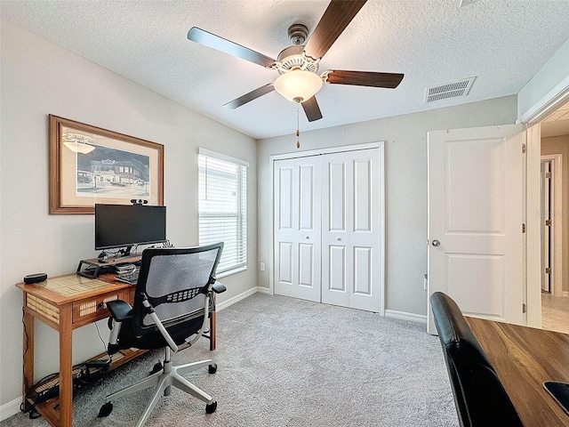 carpeted home office featuring ceiling fan and a textured ceiling