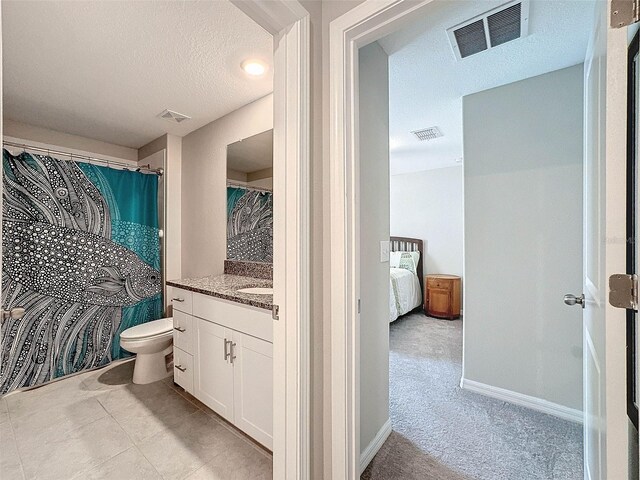 bathroom with vanity, tile patterned flooring, a textured ceiling, and toilet