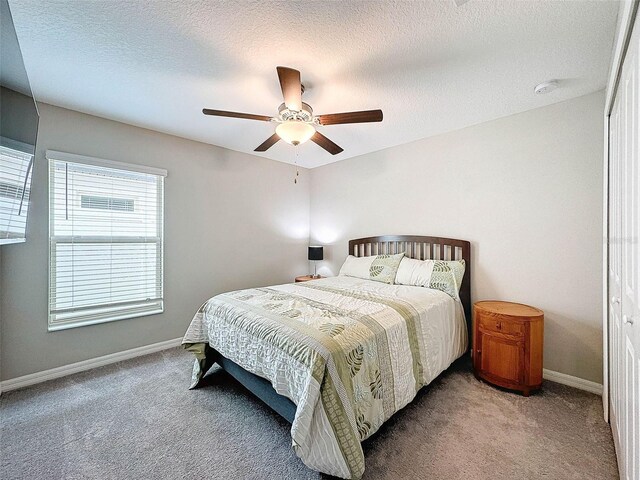 carpeted bedroom featuring a closet, a textured ceiling, and ceiling fan