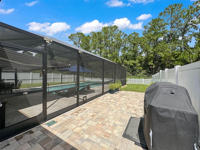 view of patio / terrace with grilling area, a fenced in pool, and glass enclosure