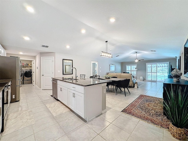 kitchen featuring stainless steel appliances, white cabinets, sink, an island with sink, and dark stone countertops