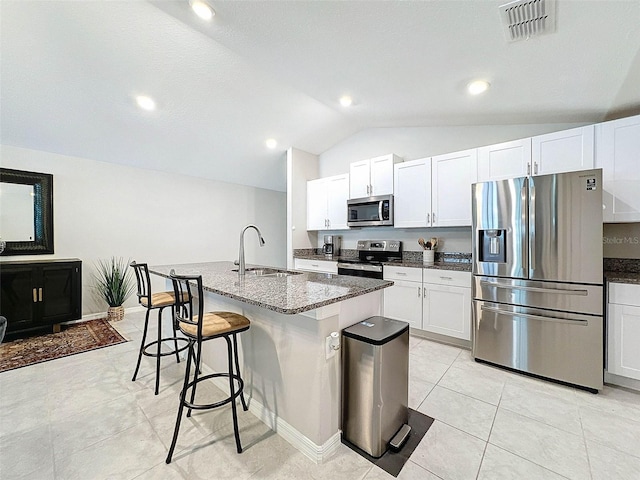 kitchen featuring stainless steel appliances, sink, a kitchen island with sink, white cabinets, and vaulted ceiling