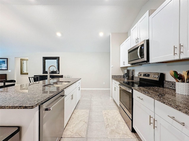 kitchen featuring a kitchen island with sink, dark stone counters, sink, and stainless steel appliances