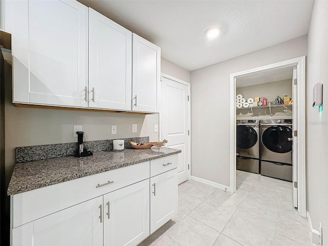 clothes washing area with a textured ceiling, washer and dryer, and light tile patterned floors