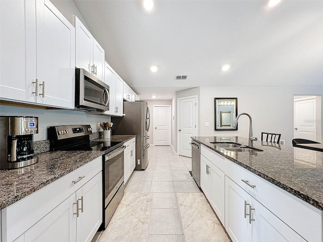 kitchen featuring dark stone countertops, white cabinetry, appliances with stainless steel finishes, and sink