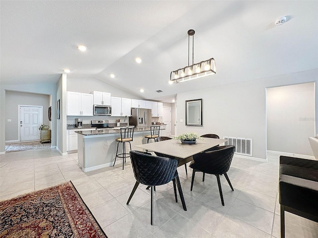 tiled dining space with sink and vaulted ceiling