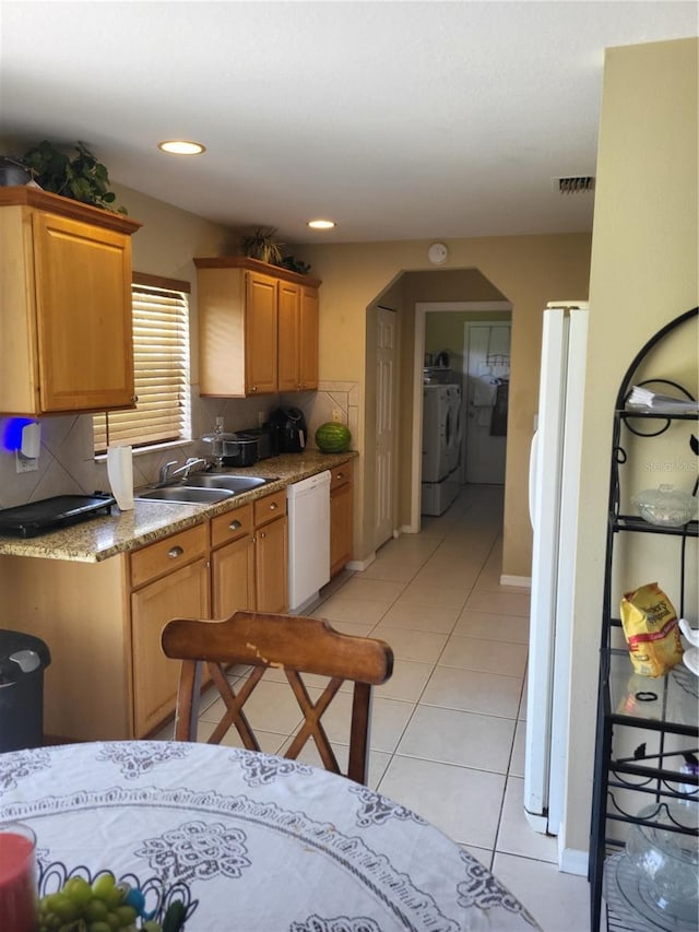 kitchen with washer and clothes dryer, white appliances, sink, decorative backsplash, and light tile patterned flooring