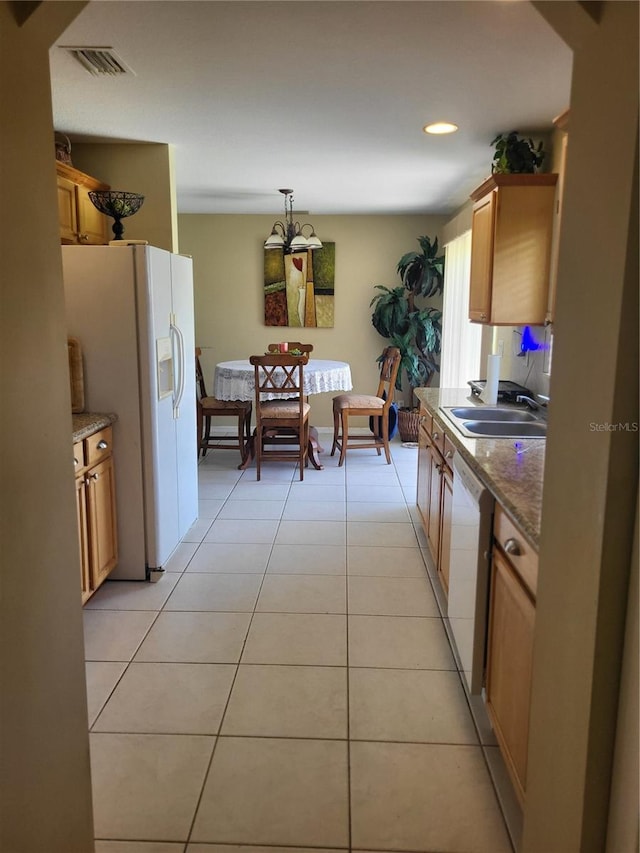 kitchen with white appliances, pendant lighting, stone countertops, light tile patterned floors, and sink