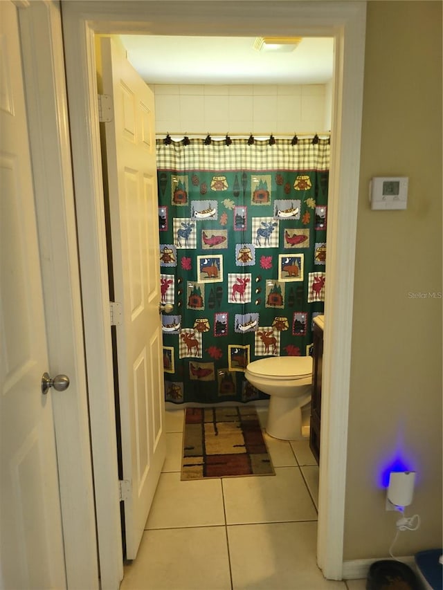 bathroom featuring tile patterned flooring, toilet, and walk in shower