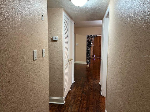 hall with a textured ceiling and dark hardwood / wood-style floors