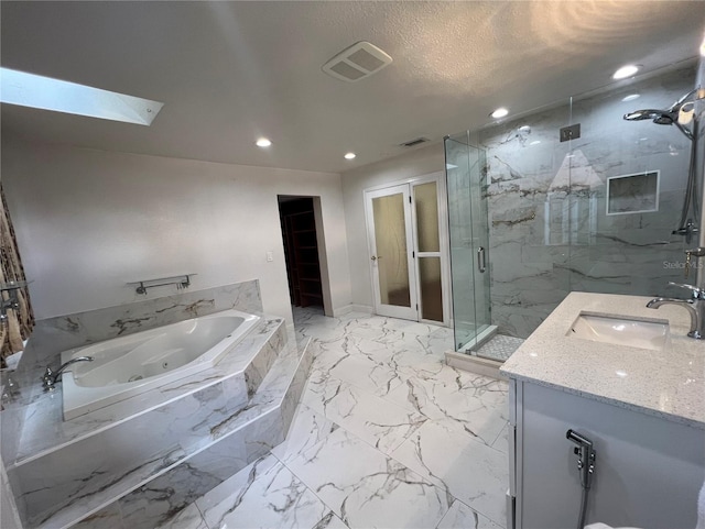 bathroom with vanity, shower with separate bathtub, a textured ceiling, and a skylight