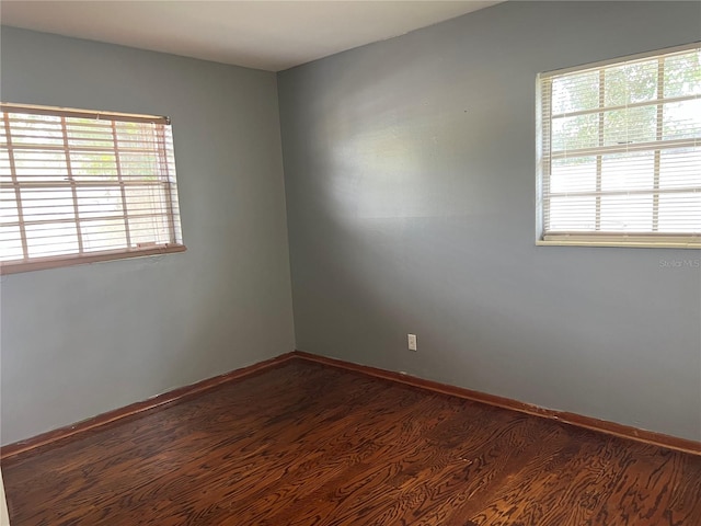 empty room featuring dark wood-type flooring and plenty of natural light