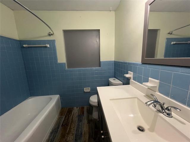 full bathroom with hardwood / wood-style floors, tile walls, toilet, vanity, and tiled shower / bath combo