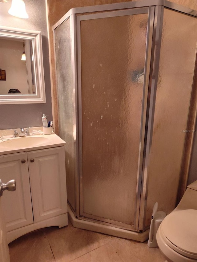 bathroom with vanity, an enclosed shower, toilet, and tile patterned flooring