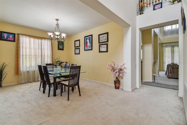 dining room featuring a chandelier, light colored carpet, and baseboards