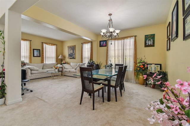 dining space featuring a notable chandelier, carpet flooring, and a healthy amount of sunlight