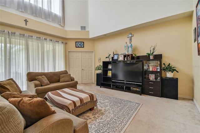 carpeted living area with a towering ceiling, visible vents, and baseboards