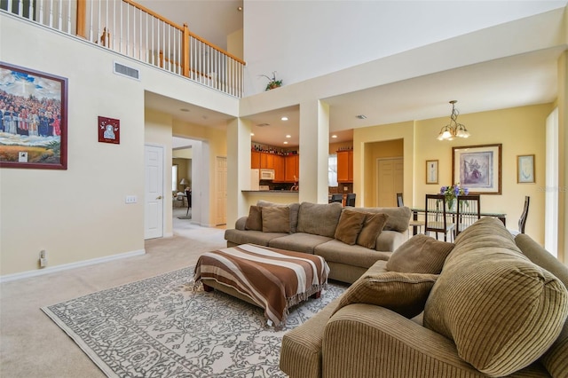 living room featuring visible vents, a high ceiling, light carpet, a chandelier, and baseboards