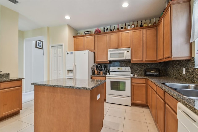 kitchen featuring white appliances, a kitchen island, backsplash, and light tile patterned flooring