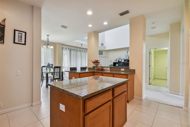 kitchen featuring dark stone counters, brown cabinets, visible vents, and light tile patterned floors