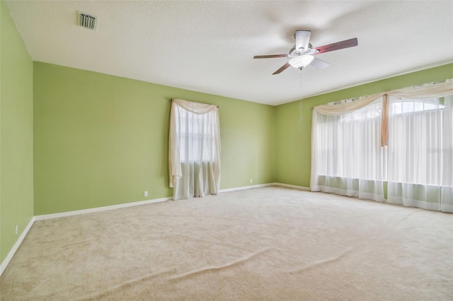 spare room with a wealth of natural light, baseboards, visible vents, and carpet